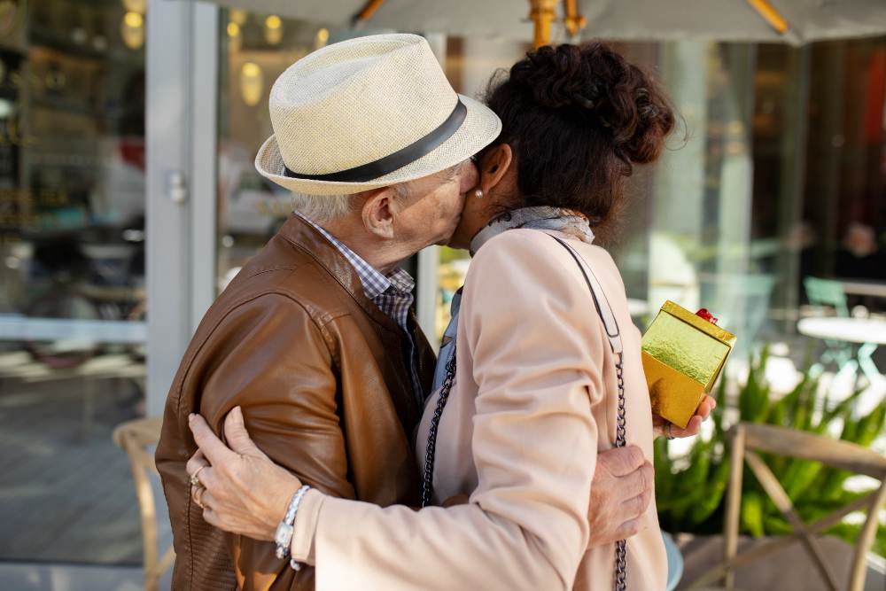 An elderly black couple are embracing each other.