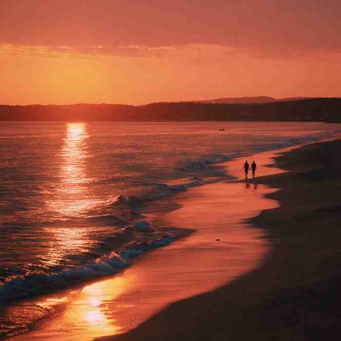 Couple walking along a beach at sunset with golden light reflecting on the ocean, creating a calm and romantic atmosphere