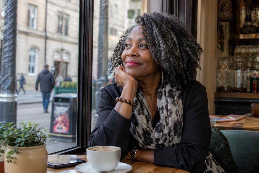 Cozy cafe moment, a smiling black mature woman 