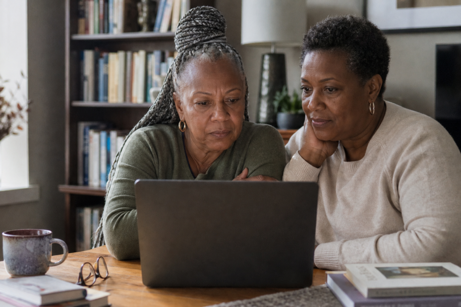 Two mature Black women reviewing an online dating conversation safely together